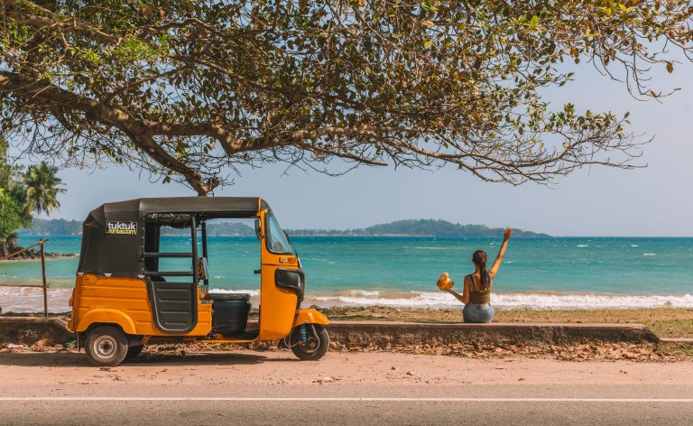 Orange tuk-tuk with women holding a king coconut.