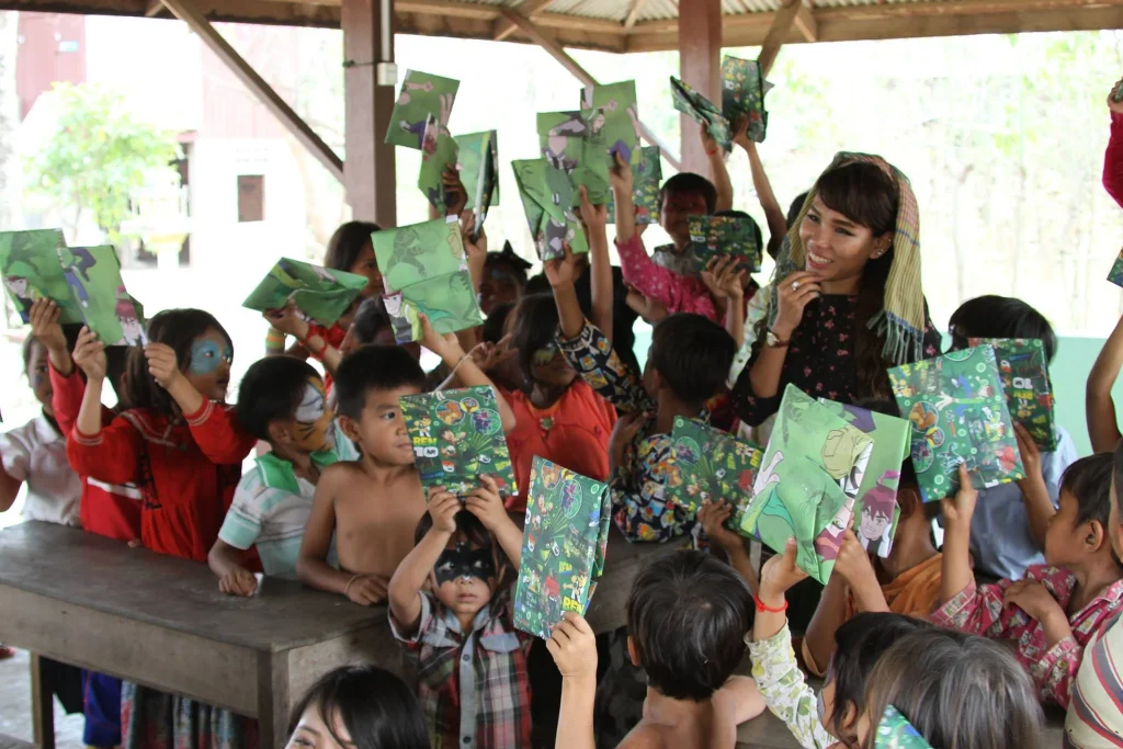 Smiling children holding up green notebooks.