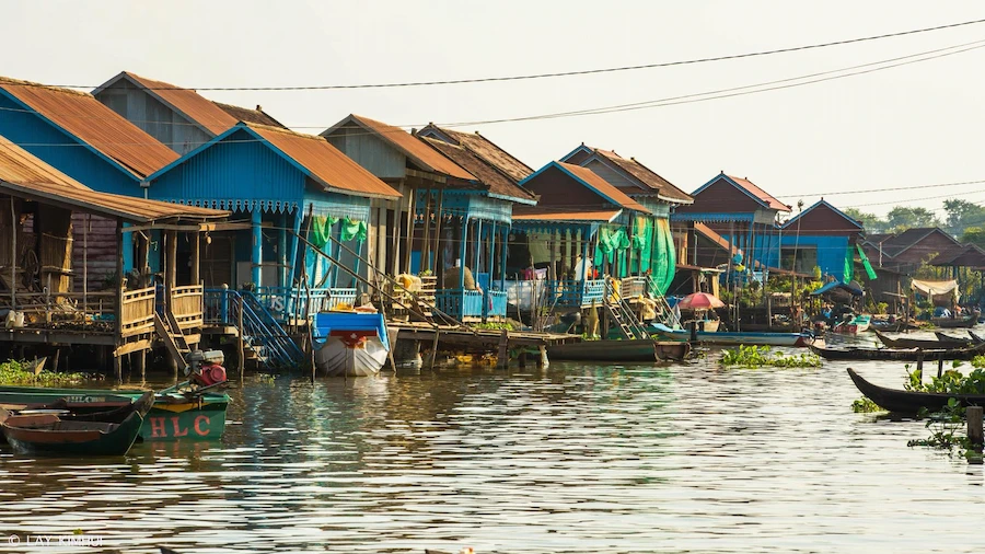 Row of colorful stilted houses on water.