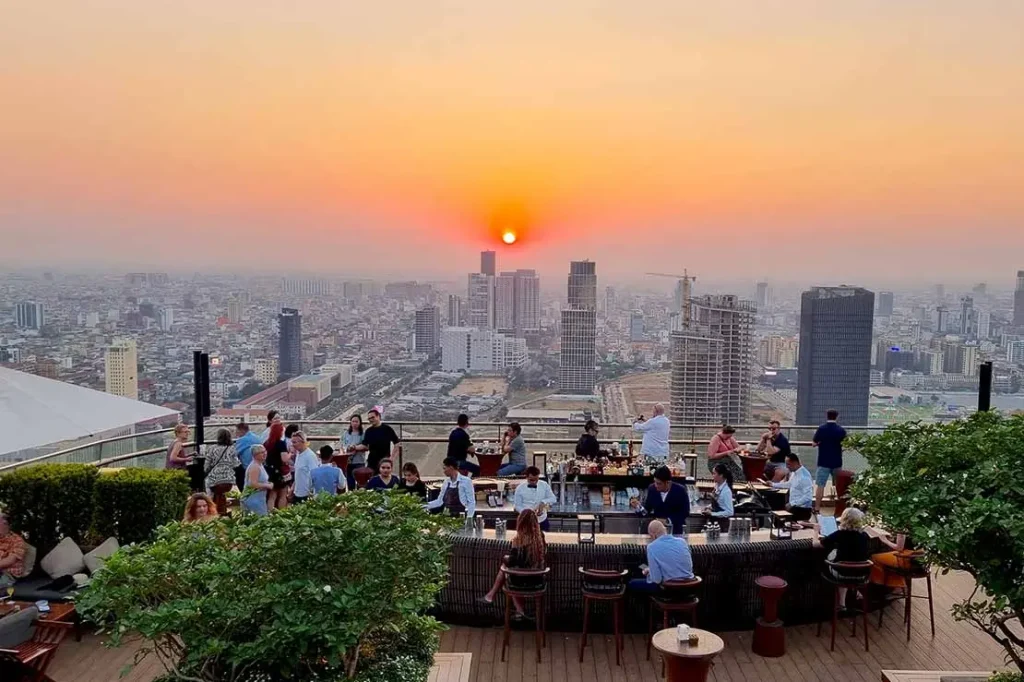 Rooftop bar overlooking city skyline at sunset.