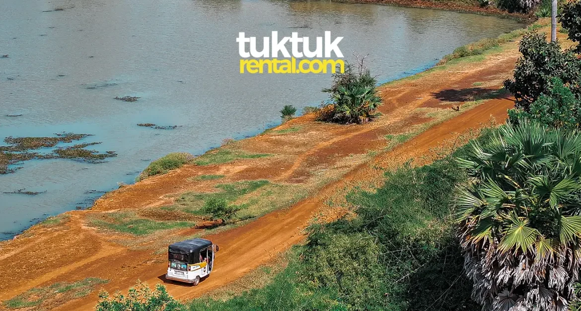 Tuk-tuk driving along a river in Cambodia.