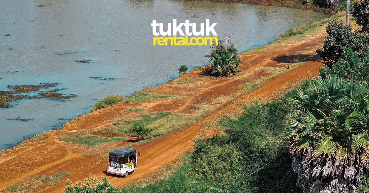 Tuk-tuk driving along a river in Cambodia.