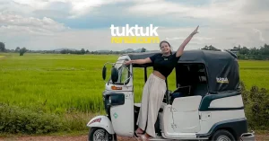 Happy woman posing in tuk-tuk near rice fields.