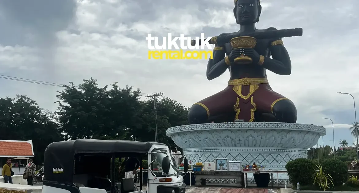 Tuk-tuk parked near giant Ta Dambong statue.