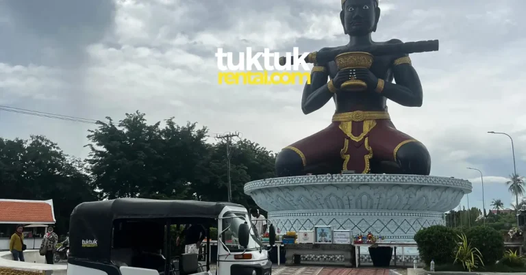 Tuk-tuk parked near giant Ta Dambong statue.