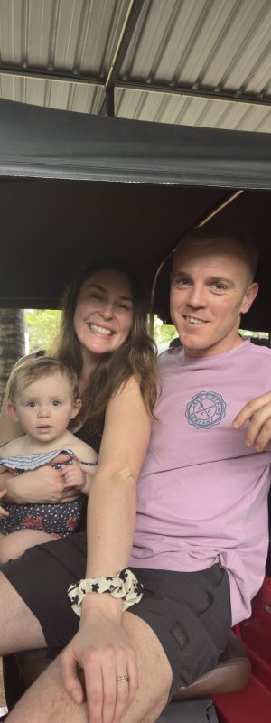 A family of three riding in a tuk-tuk.