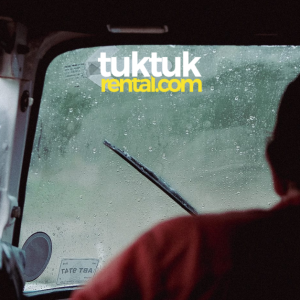 A picture of men riding a tuk-tuk with a windshield and a logo.