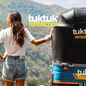 A woman is holding a tuk-tuk in a forest view.