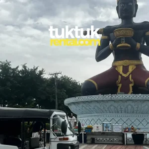 Tuk-tuk parked near giant Ta Dambong statue.
