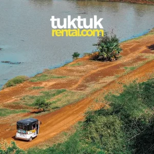 Tuk-tuk driving along a river in Cambodia.